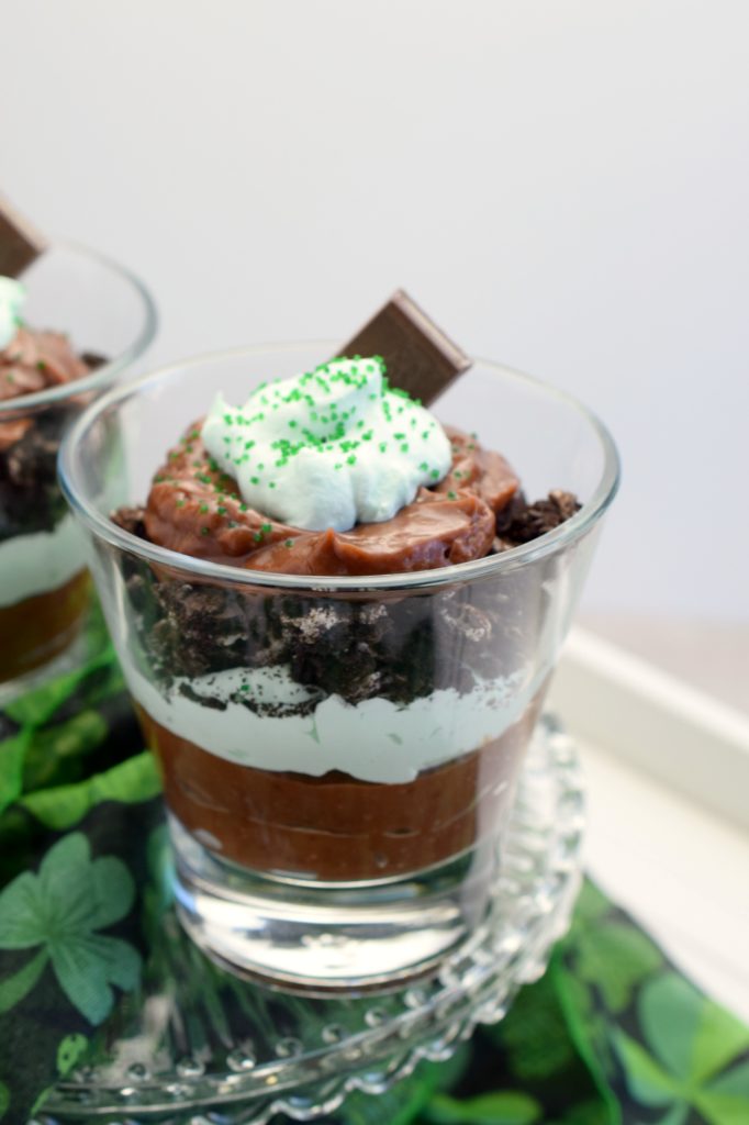 layered dessert in glass with St. Patrick's day fabric over white board